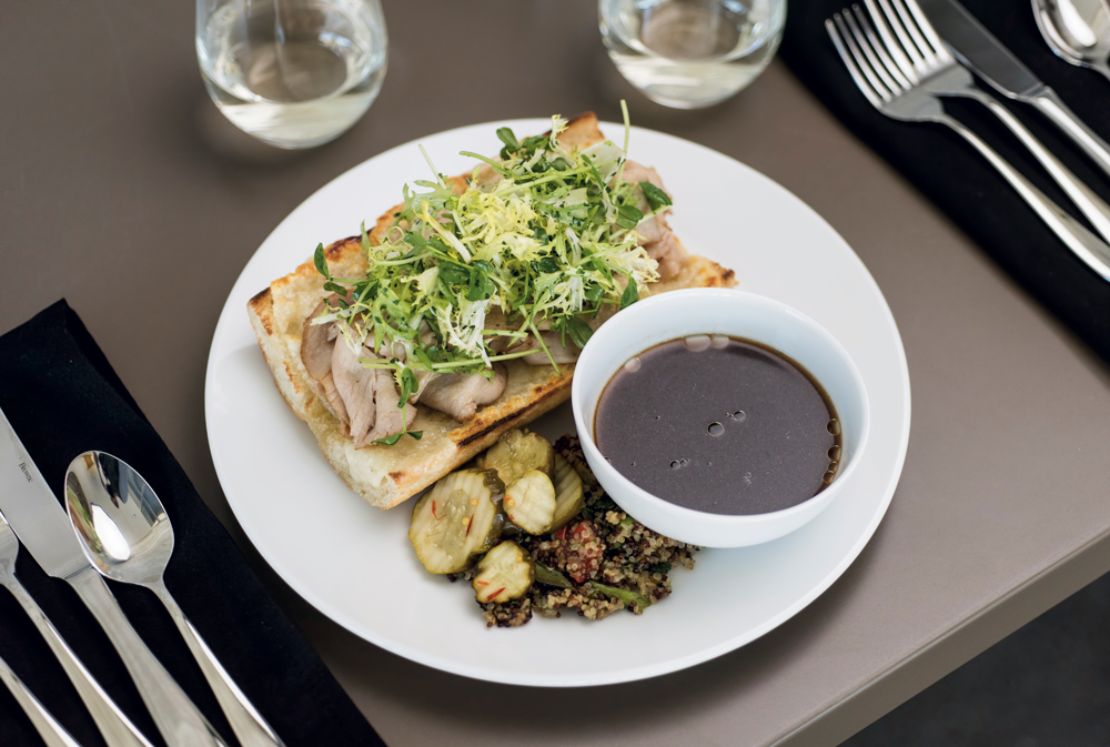 Roasted pork loin and a parsley frisée salad on a house baguette with a French dip