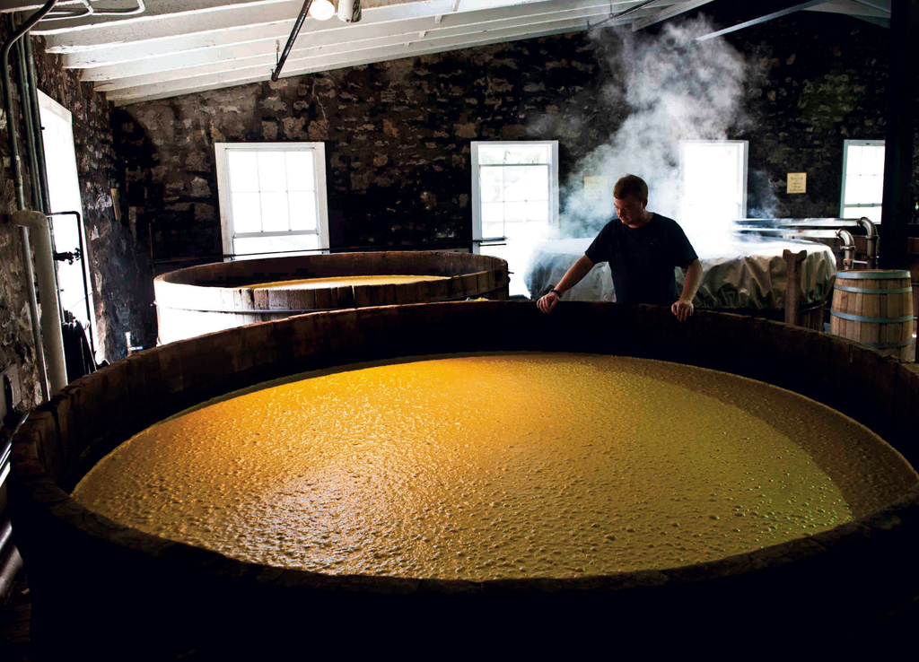 In large cypress fermenting tubs, the mash bubbles as the yeast converts sugar into alcohol.